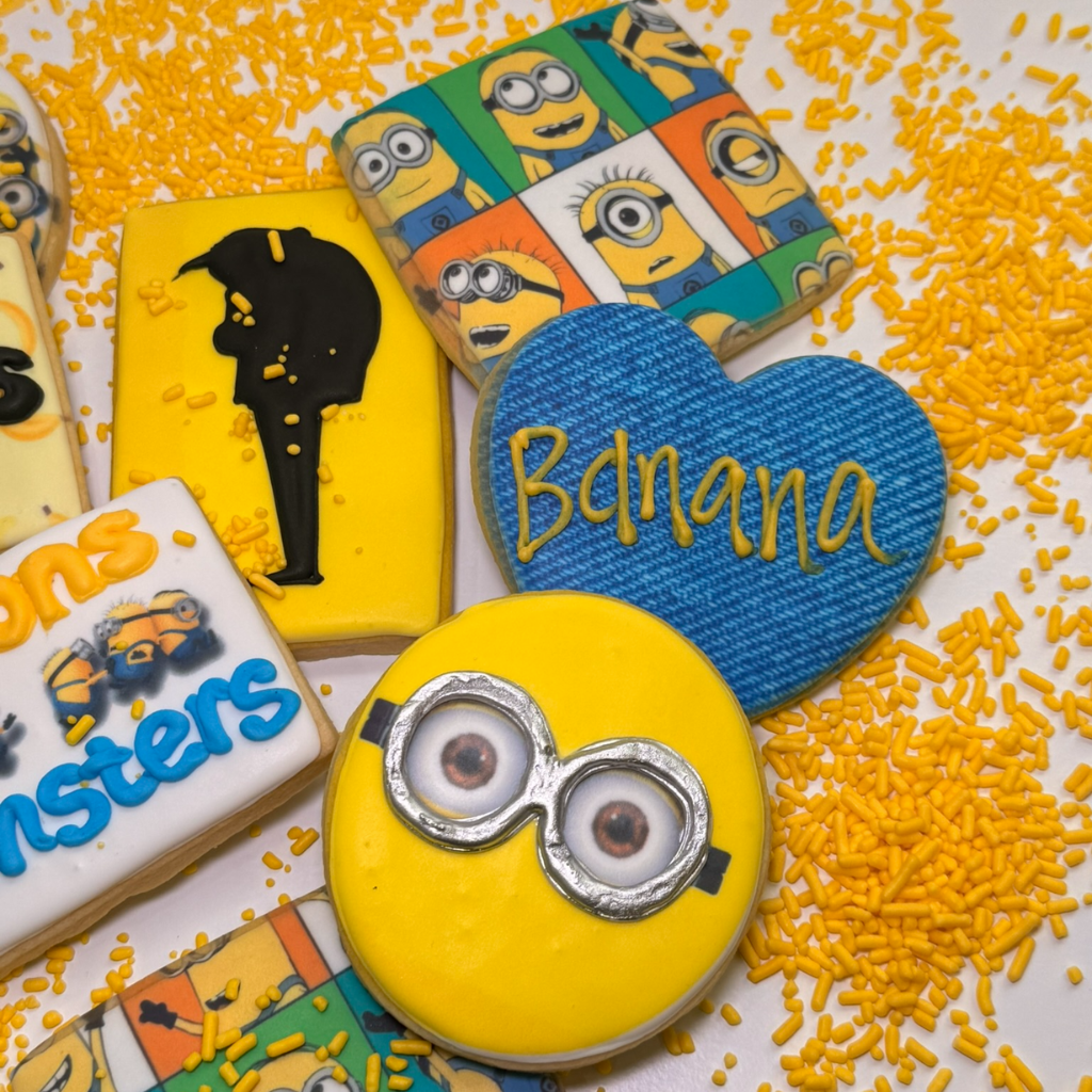 Assorted Minions cookies with yellow sprinkles on white.