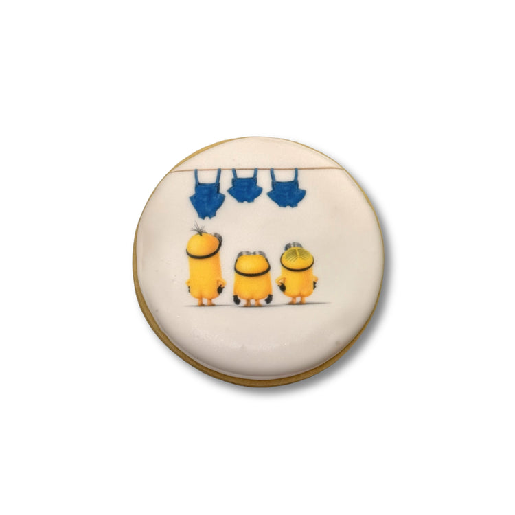 Round Minions cookie with three characters and blue overalls.