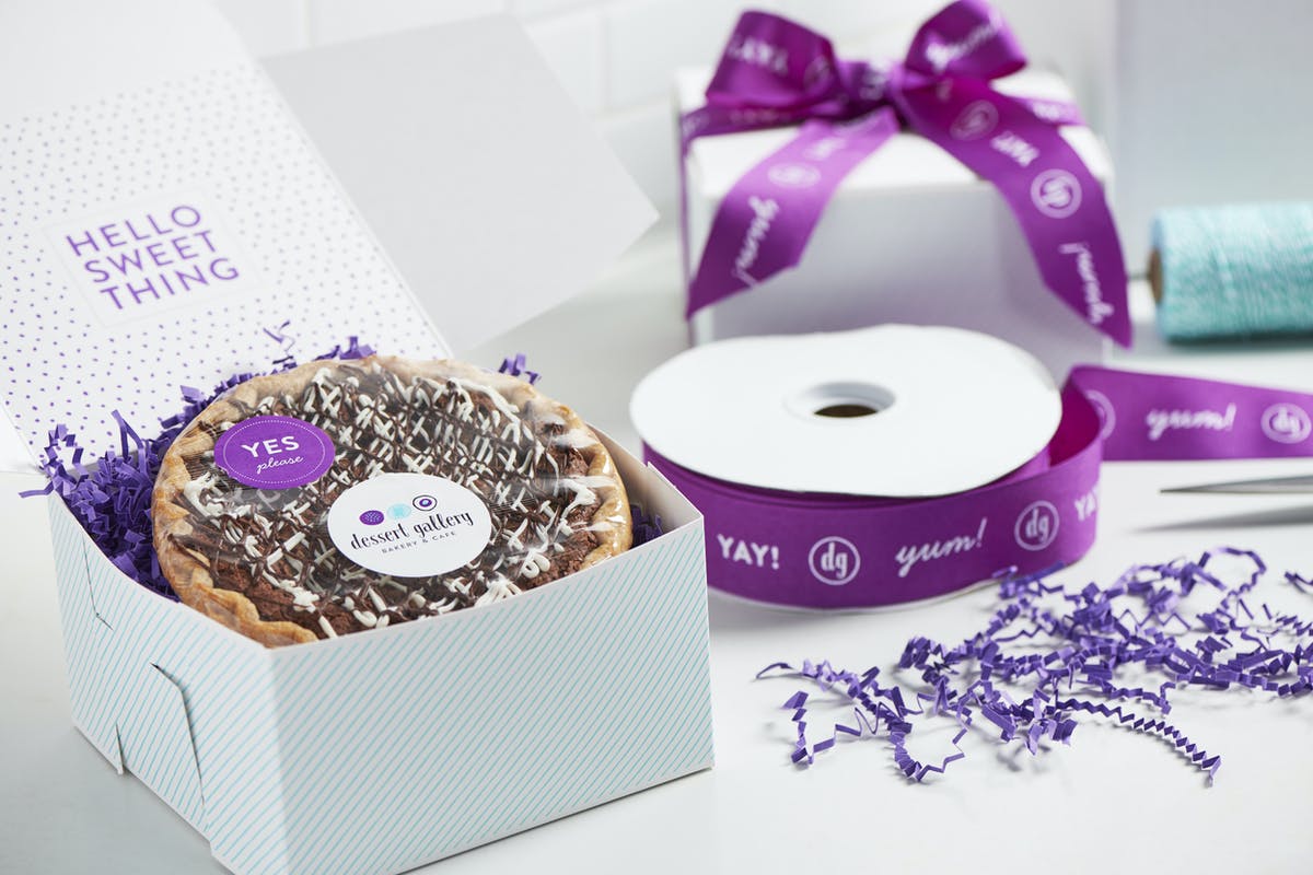 Chocolate pie in a gift box with purple ribbon and confetti