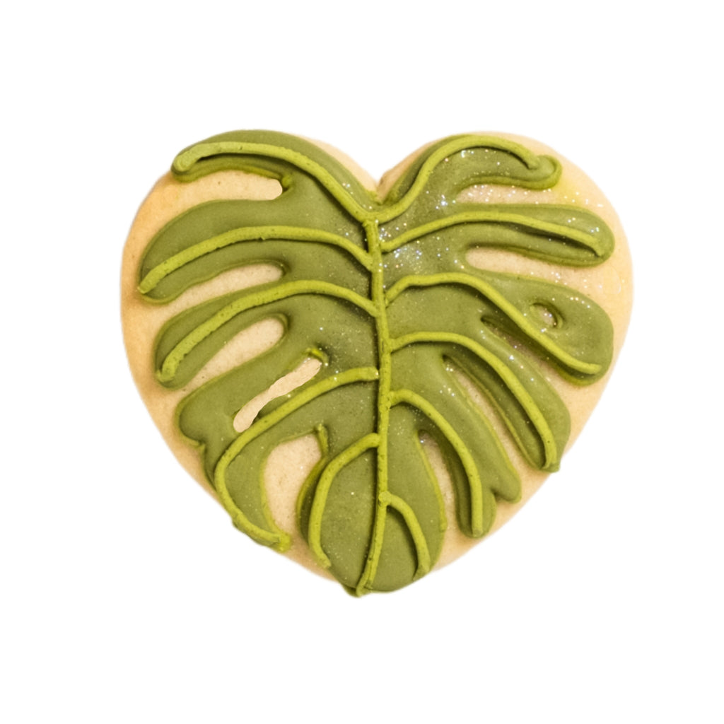 Heart-shaped cookie with green monstera leaf icing.