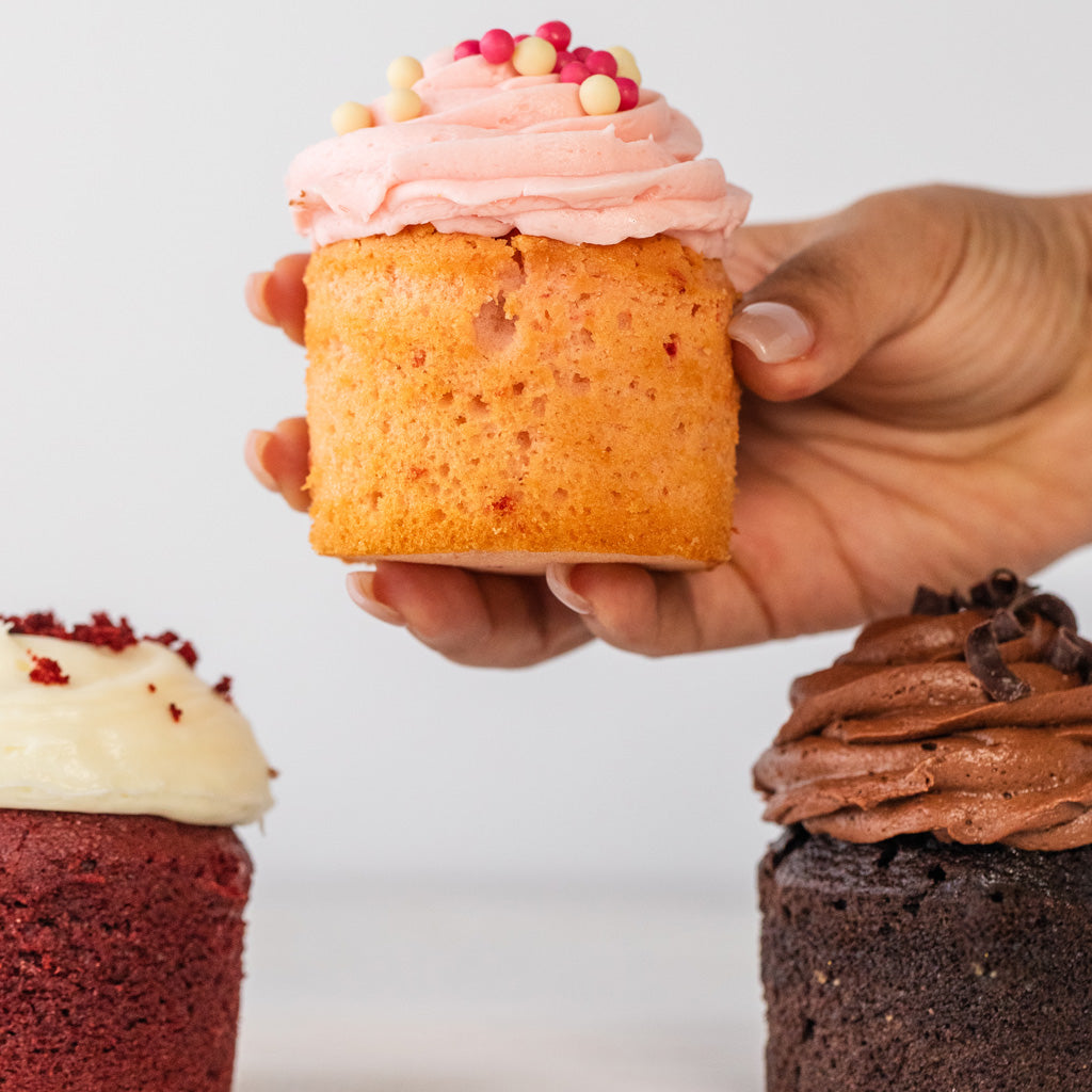 Assorted cupcakes with pink, red velvet, and chocolate frosting.
