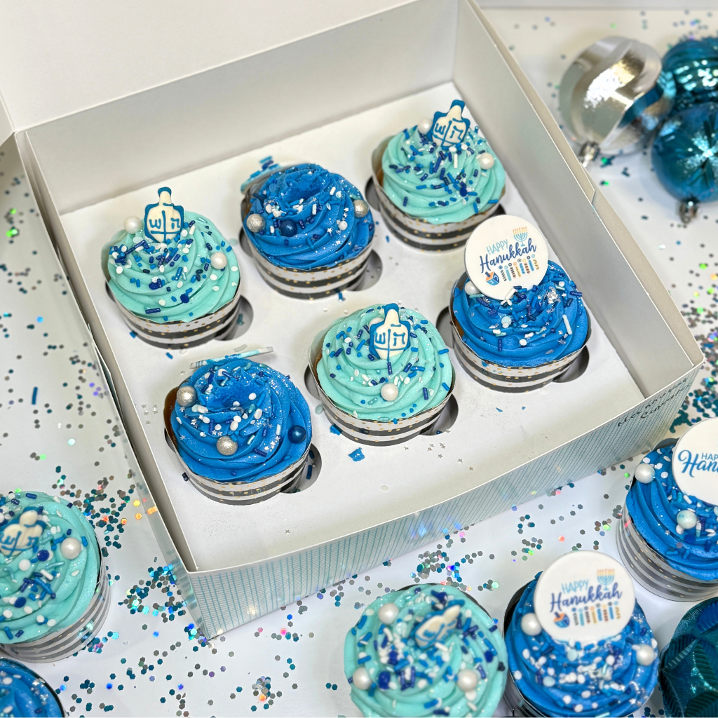 Hanukkah cupcakes with blue frosting and dreidel toppers.