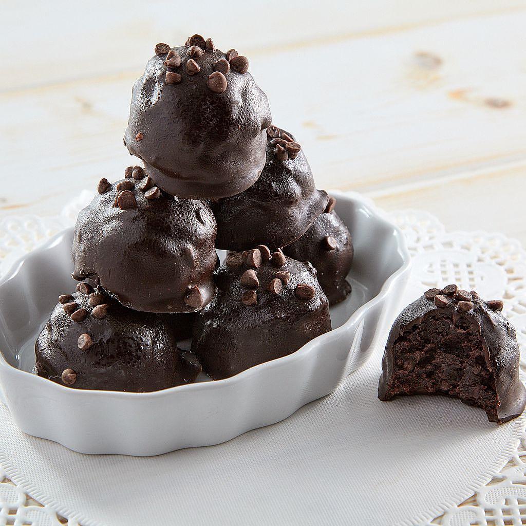 Chocolate chip cake balls stacked in a white ceramic dish.