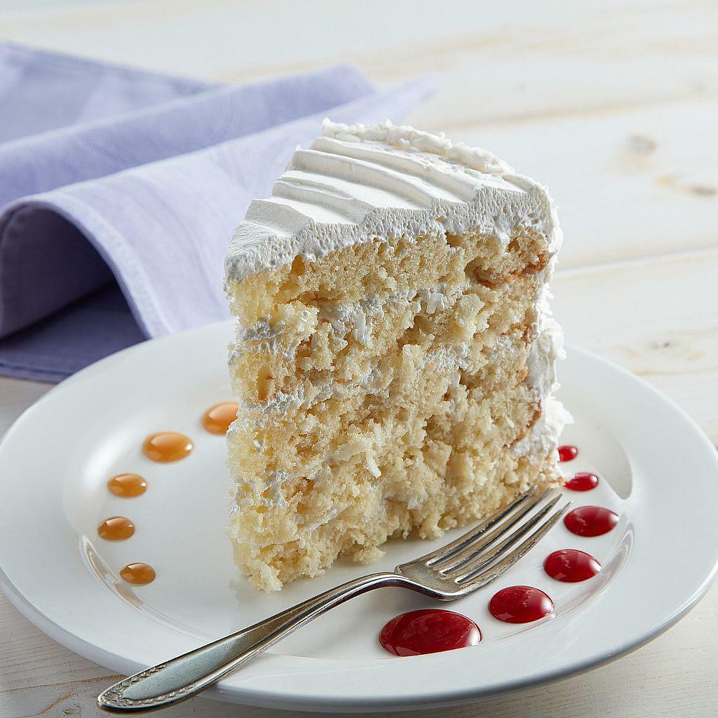 Coconut cream cake slice with white frosting on a plate.