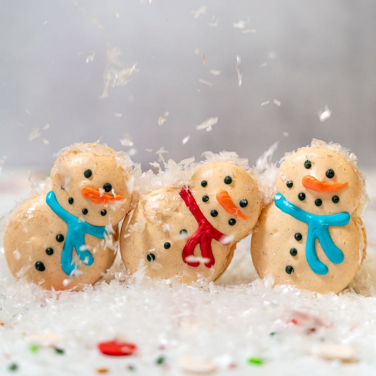 Snowman macarons with colorful icing scarves in faux snow.