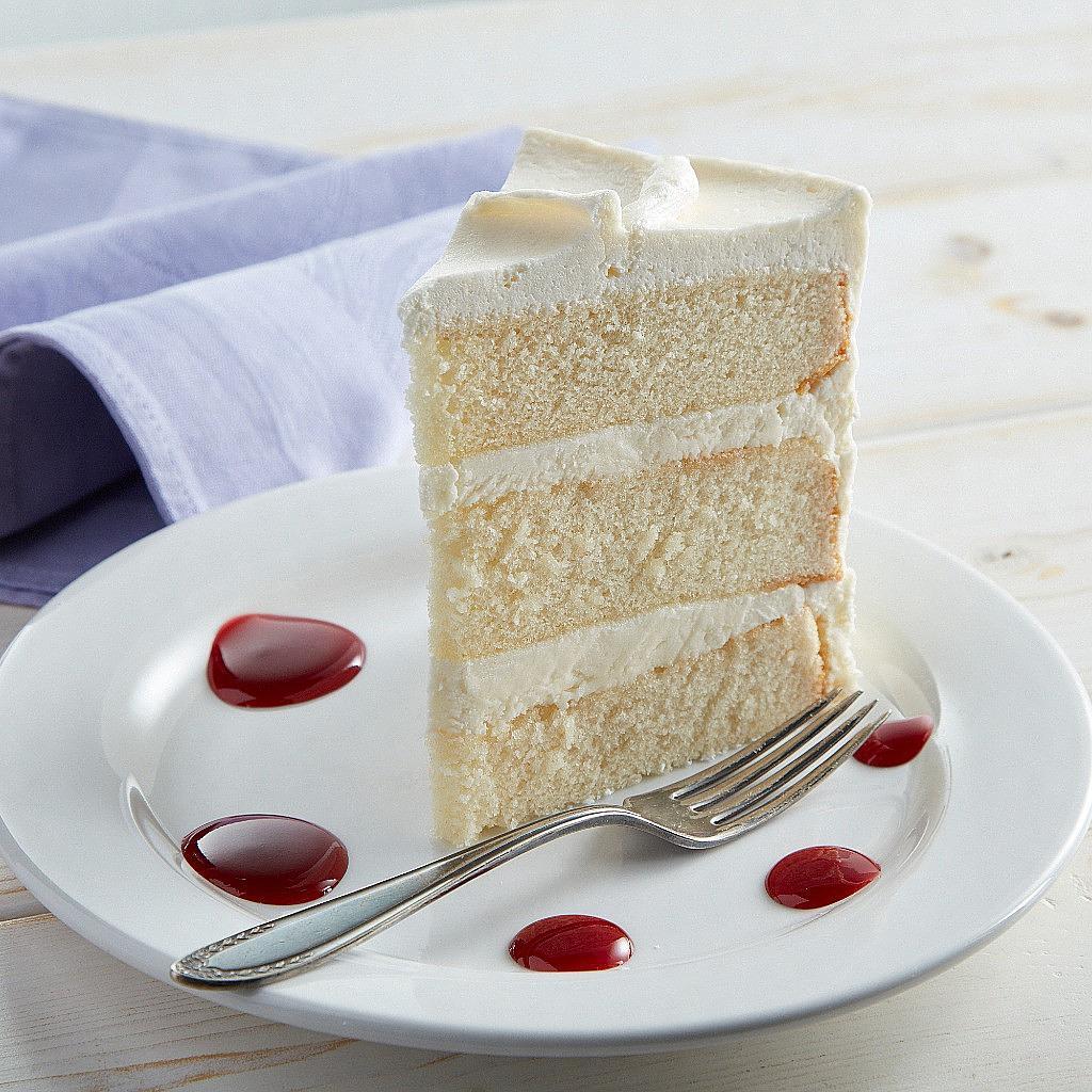 Slice of 9-inch French vanilla cake with berry sauce on a plate.