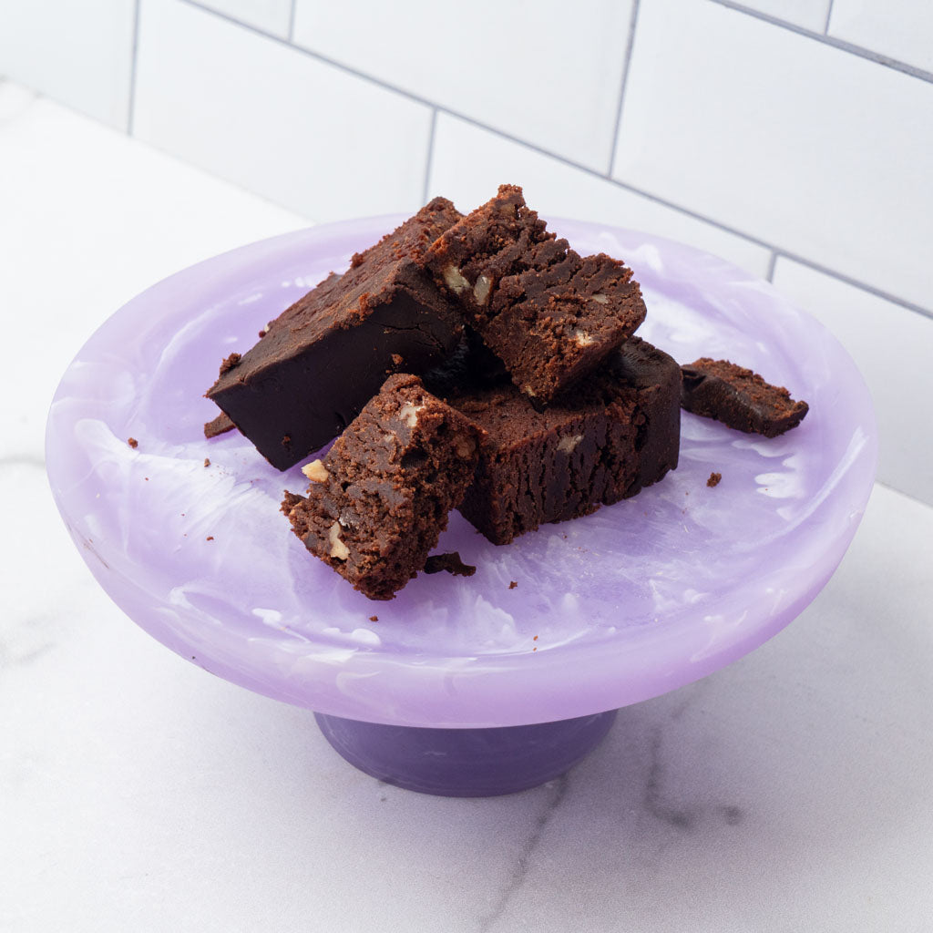 Edges chocolate brownie pieces on a purple marble cake stand