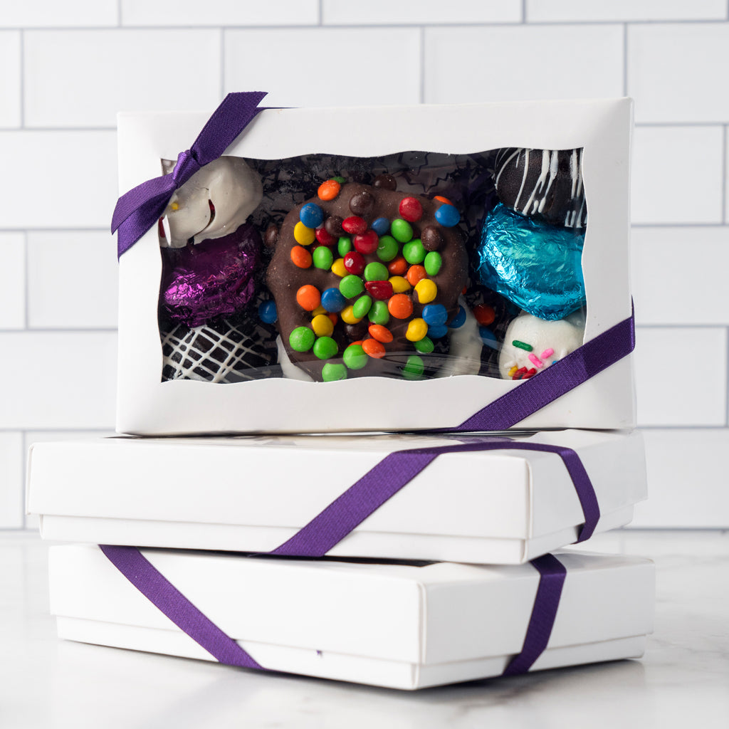 Chocolate Dipped Delights in white boxes with purple ribbons.