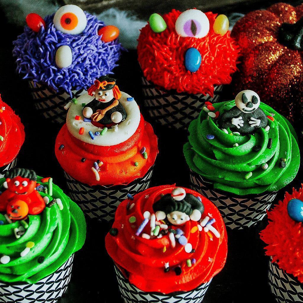 Halloween cupcakes with colorful frosting and monster toppers.