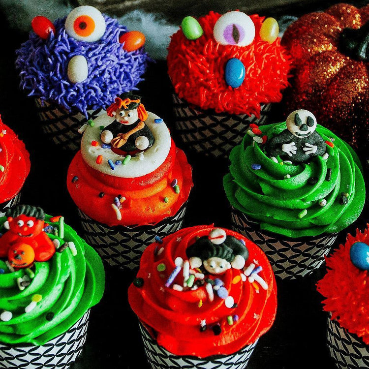 Halloween cupcakes with colorful frosting and monster toppers.