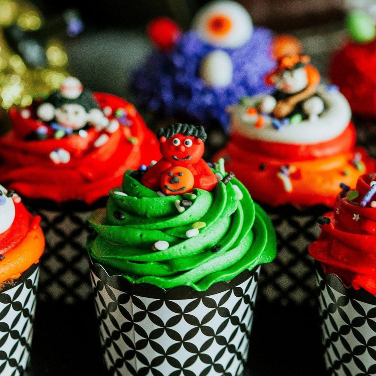 Halloween cupcakes with colorful frosting and monster toppers.