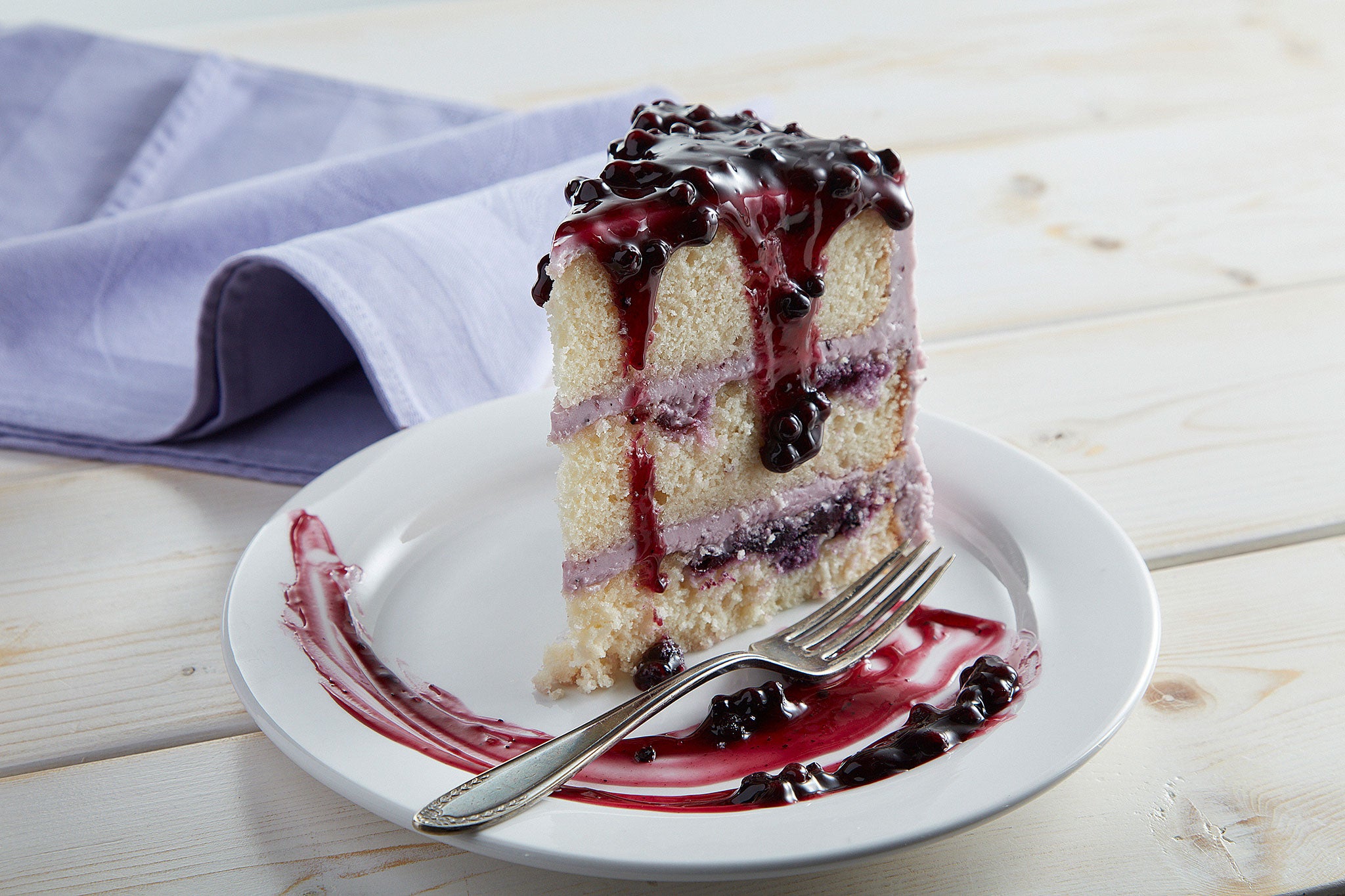 Slice of blueberry layer cake with fruit topping on a plate
