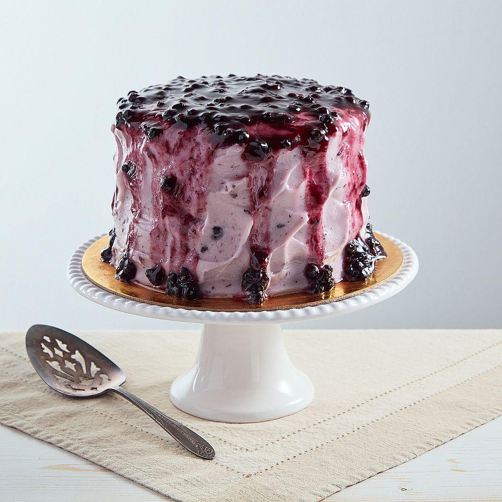 6-inch lemon blueberry cake with purple berry glaze on a stand