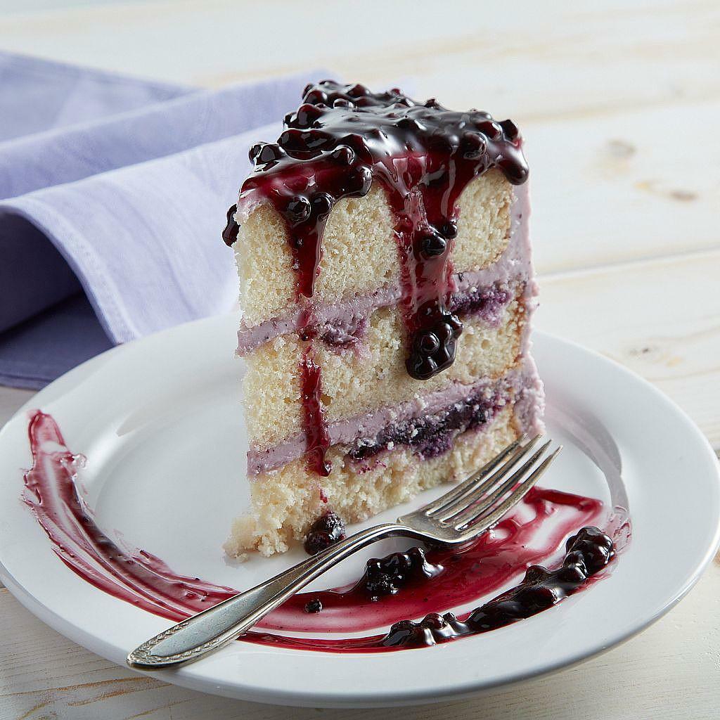 Slice of 9-inch lemon blueberry cake with berry glaze