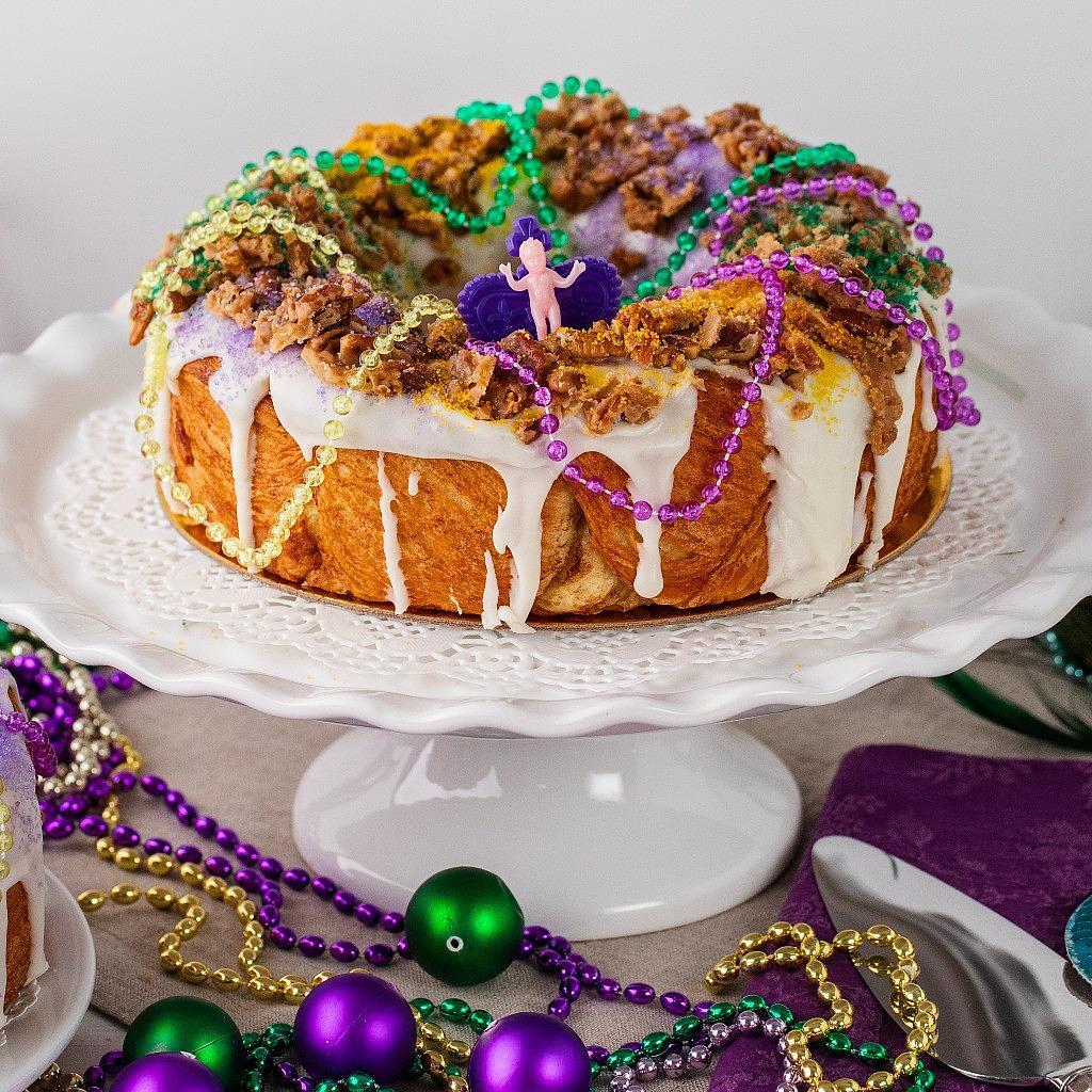 Mardi Gras 2025 king cake with purple, green, and gold beads.
