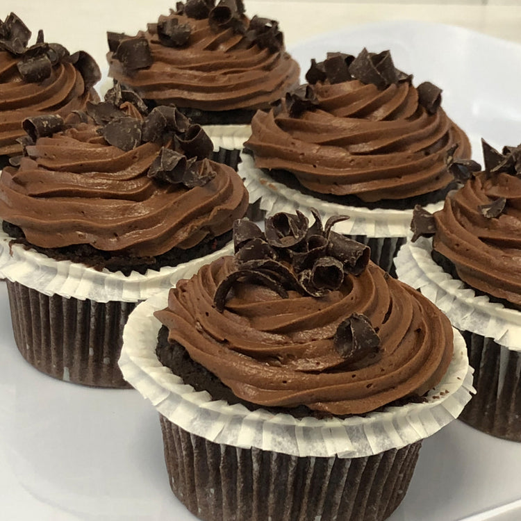 Mini chocolate cupcakes with swirls of frosting and shavings.