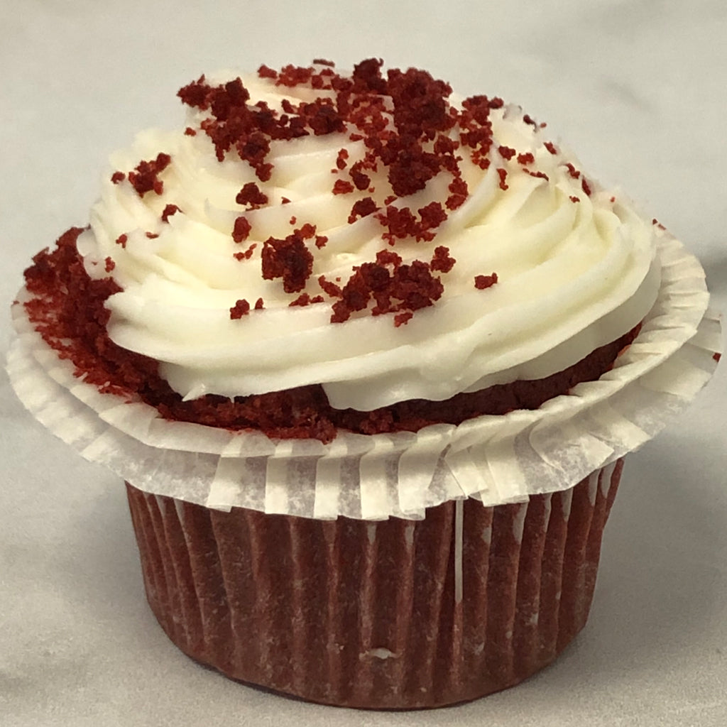 Mini red velvet cupcake with white cream frosting and red crumbs.