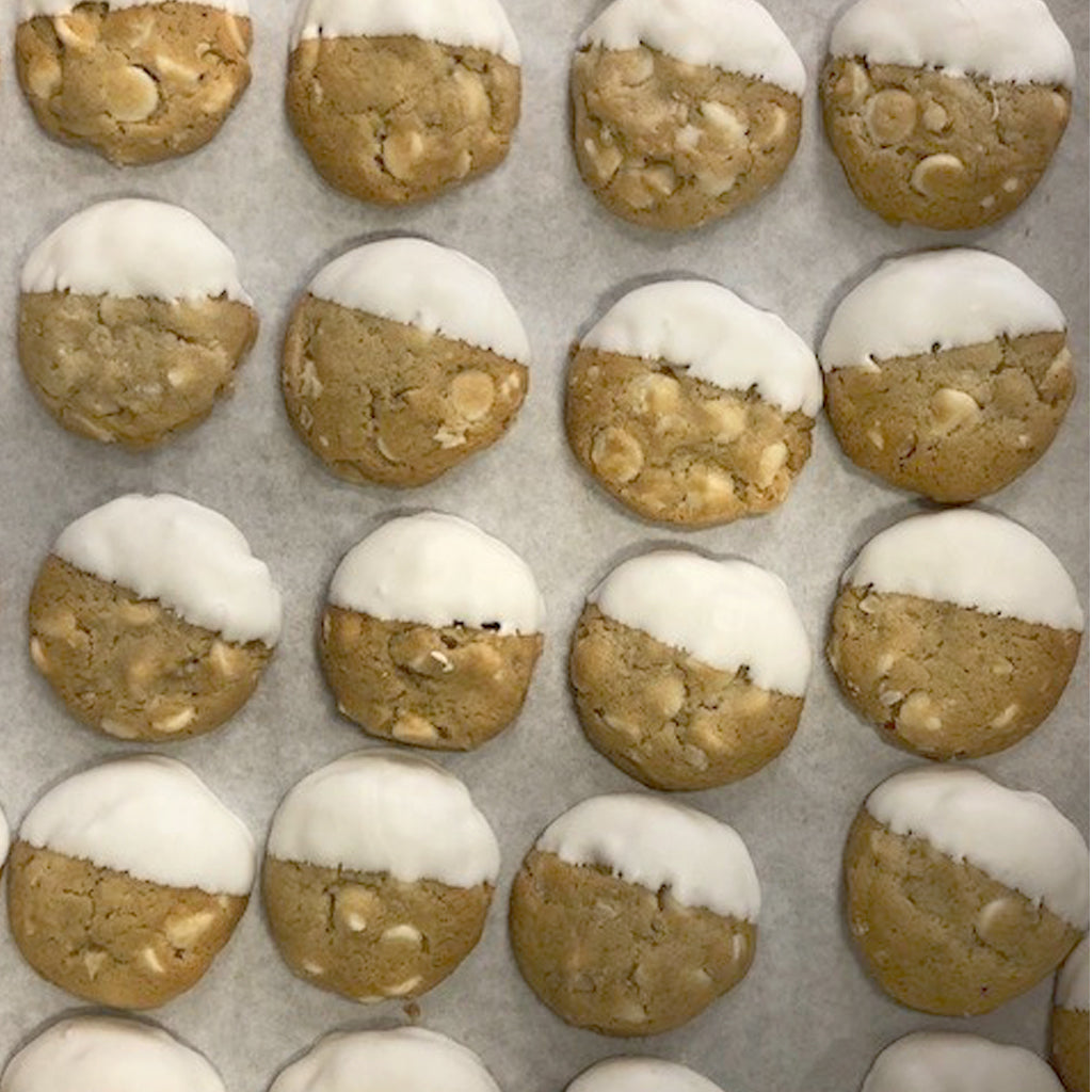Miniature cookies dipped in white chocolate on parchment paper