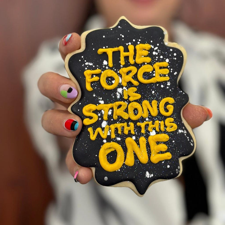 Star Wars cookie with yellow icing on a black starry background.