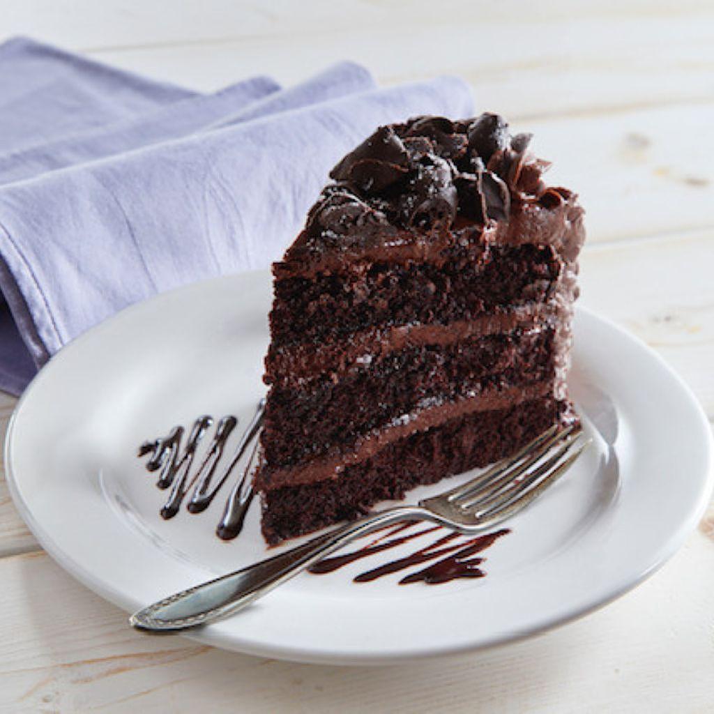 Slice of triple-layer chocolate cake on a white plate