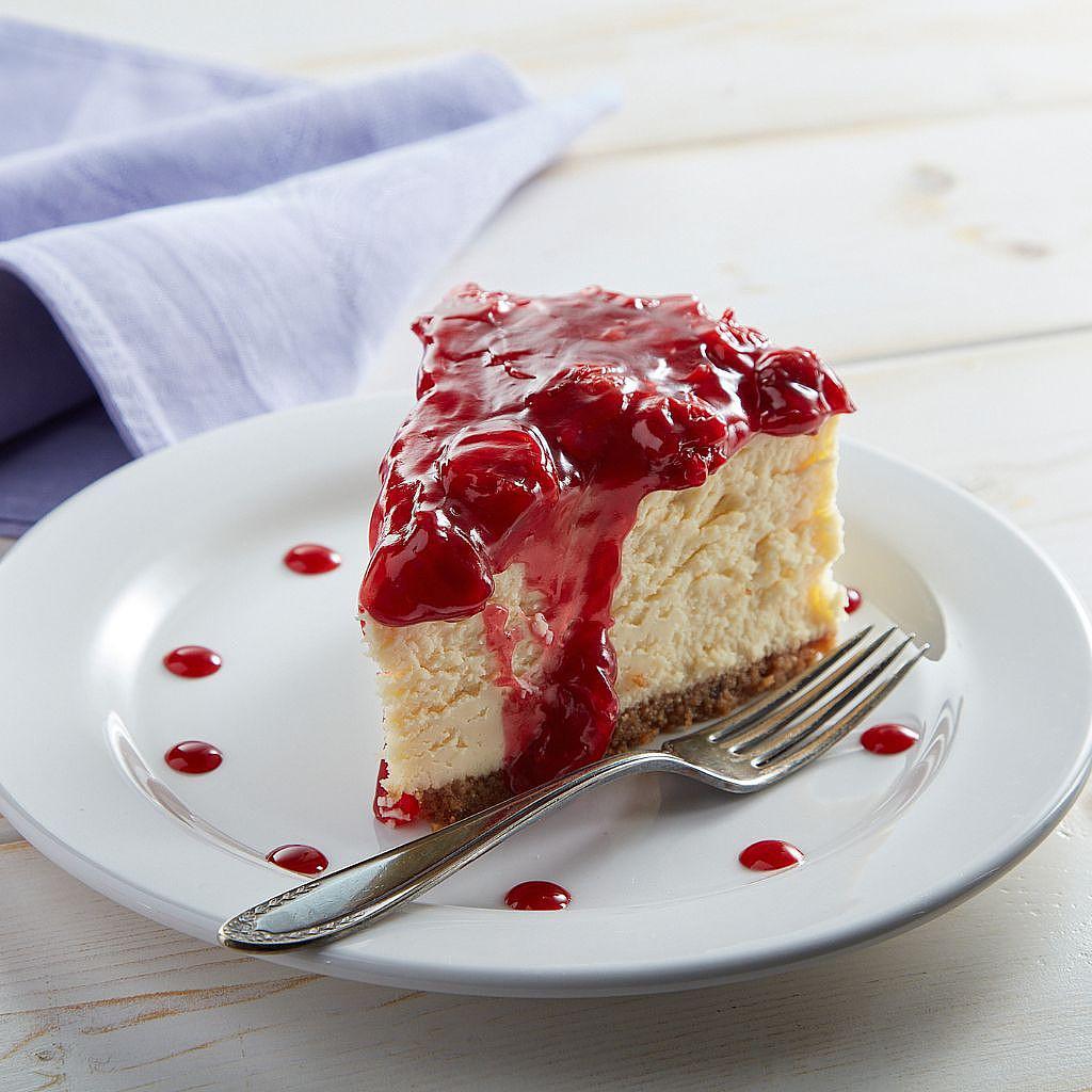 Slice of cherry cheesecake on a white plate with a fork