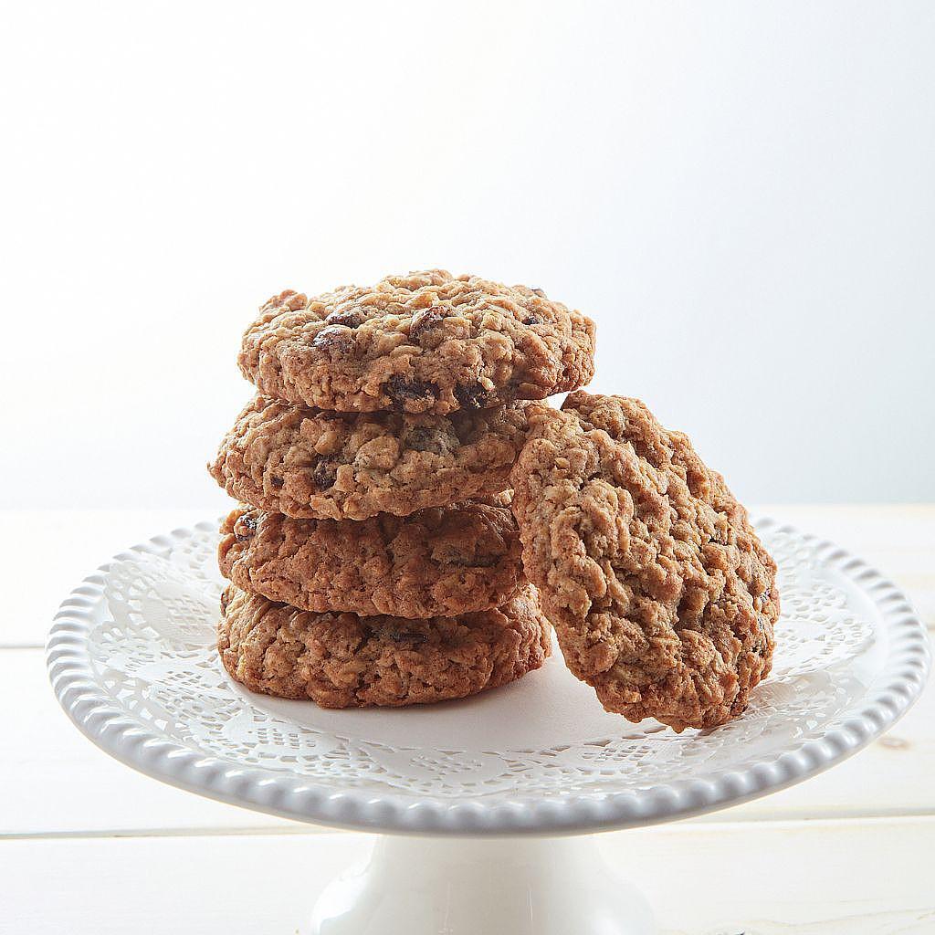 Stack of oatmeal raisin walnut cookies on a white cake stand