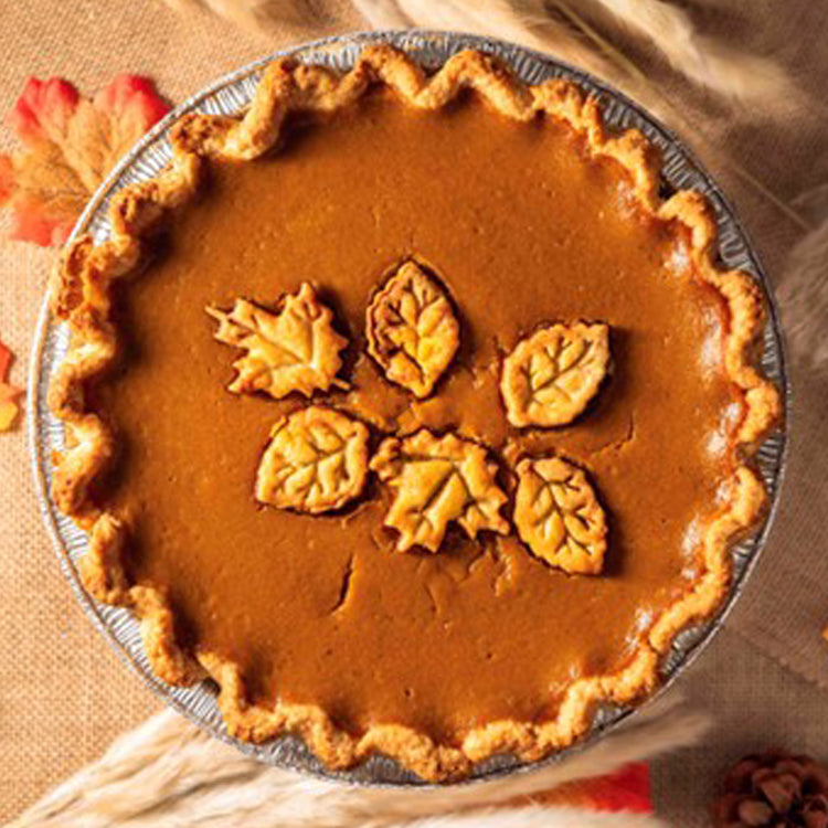 Rustic pumpkin pie topped with decorative pastry leaves.