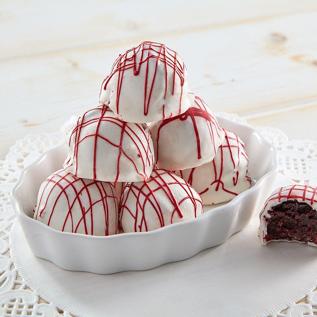 Red velvet cake balls with white chocolate and red drizzle.