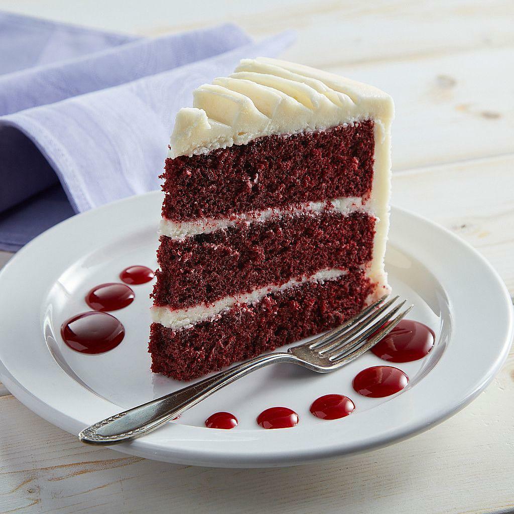 Slice of 9-inch red velvet cake with white frosting on a plate
