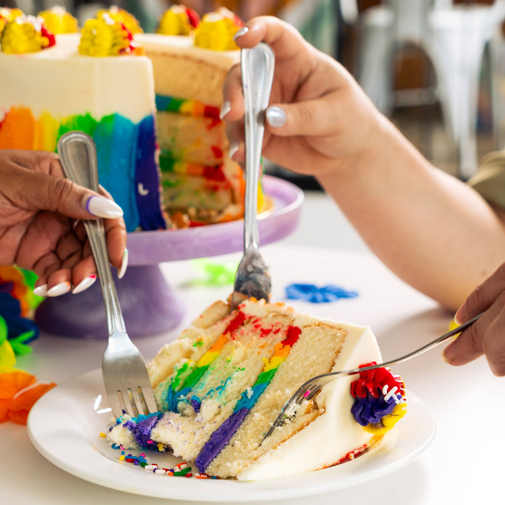 9-inch Pride cake with rainbow layers being served on a plate.