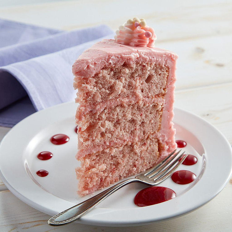 Strawberry Dream Cake slice with pink frosting on a white plate.
