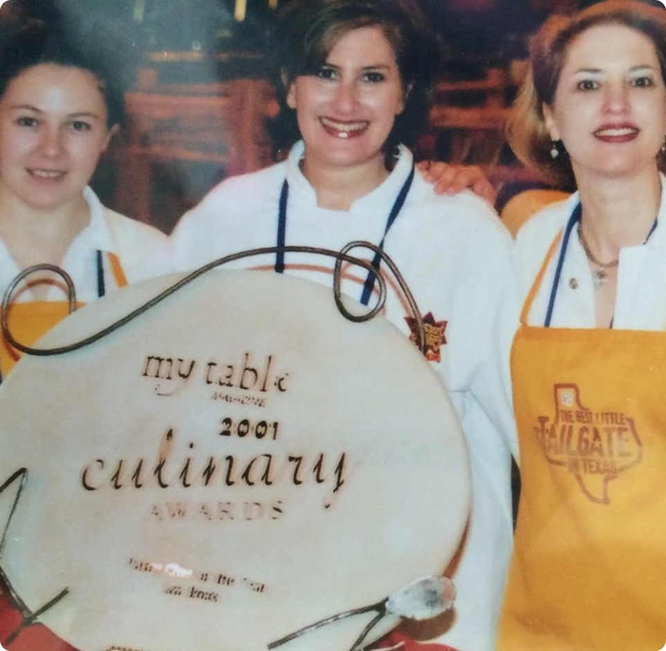 Three women in chef uniforms holding a 2001 culinary award.