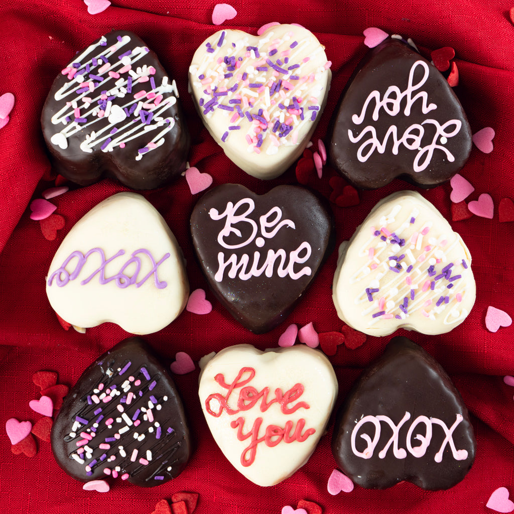 Petit Four Hearts with chocolate and icing on red fabric.