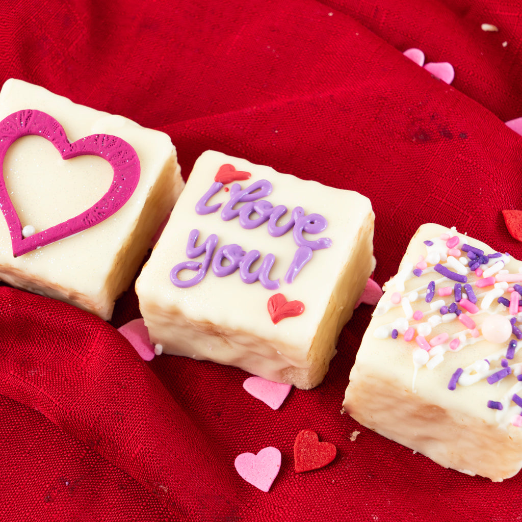 Valentine Petit Fours with heart and text icing on red fabric
