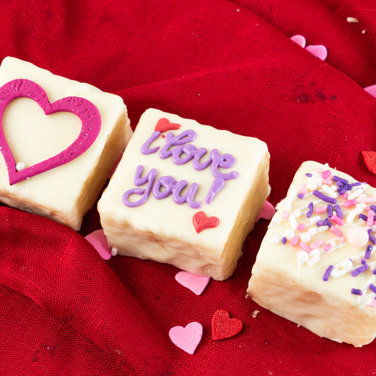Valentine Petit Fours with heart and text icing on red fabric