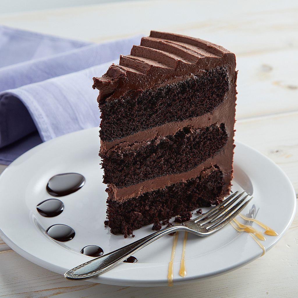 Slice of triple-layer chocolate cake on a white plate