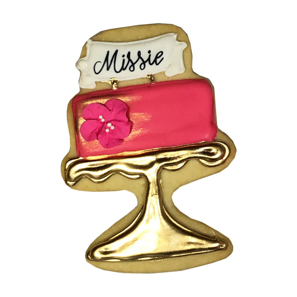 Birthday cake cookie on a gold stand with a custom Missie banner