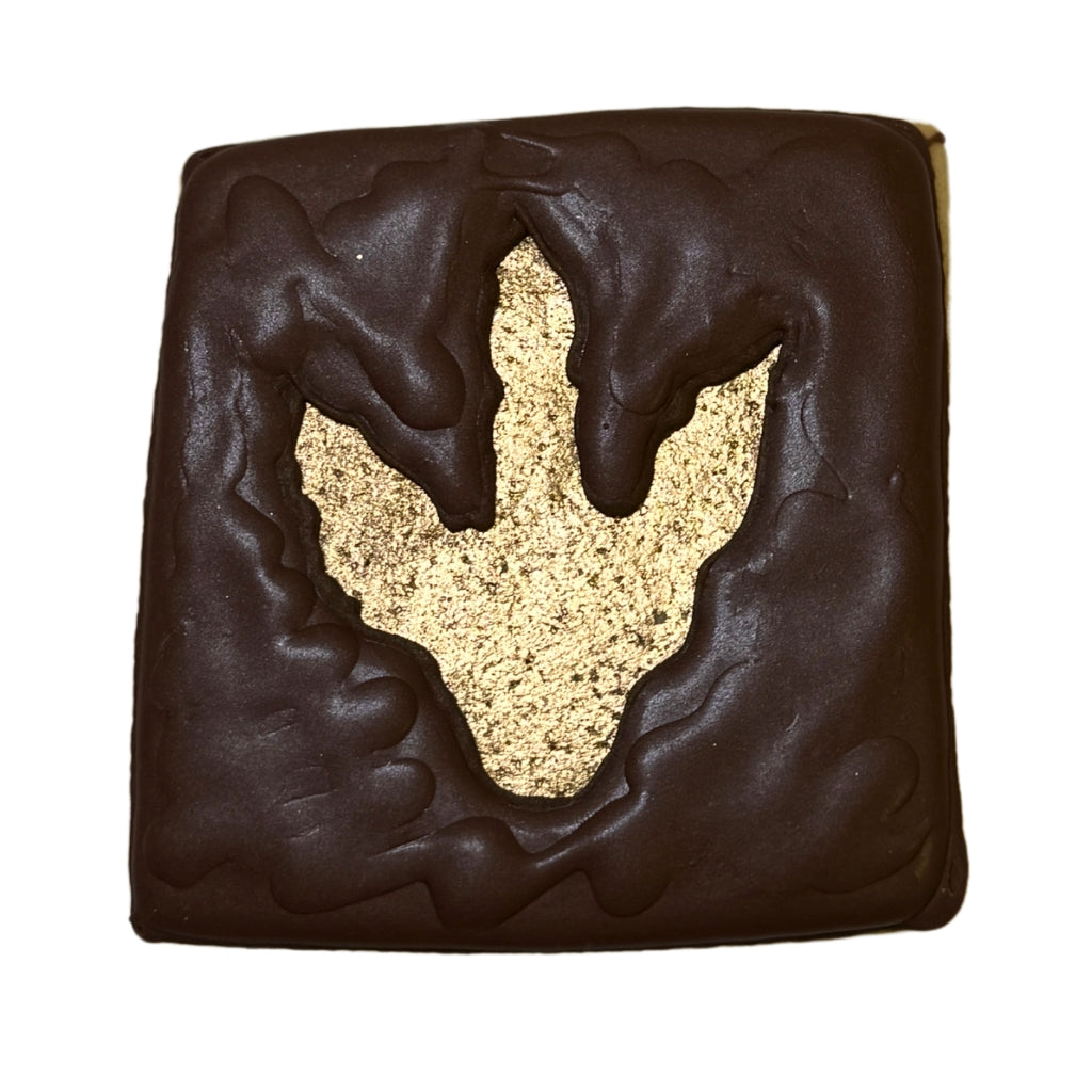 Jurassic Cookie with a gold dinosaur footprint cutout.