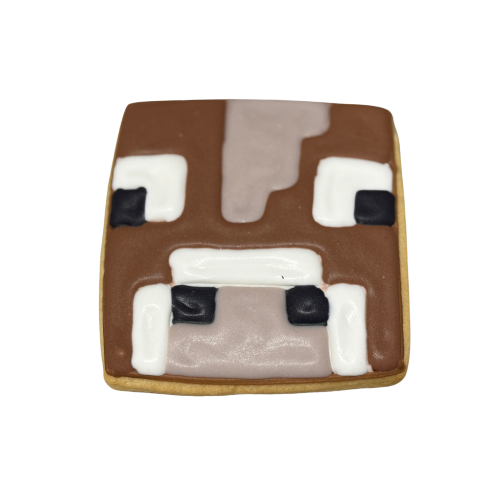 Minecraft cow-shaped cookie with brown and white icing.