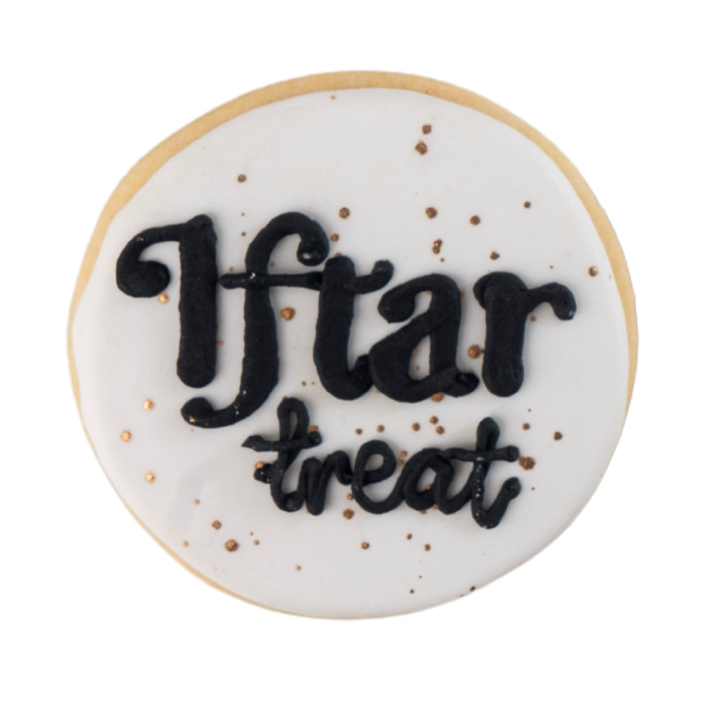 Round butter cookie with white icing and black Iftar treat text.