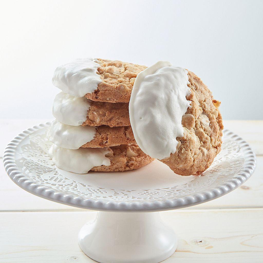 White-dipped white chocolate macadamia nut cookies on a stand.