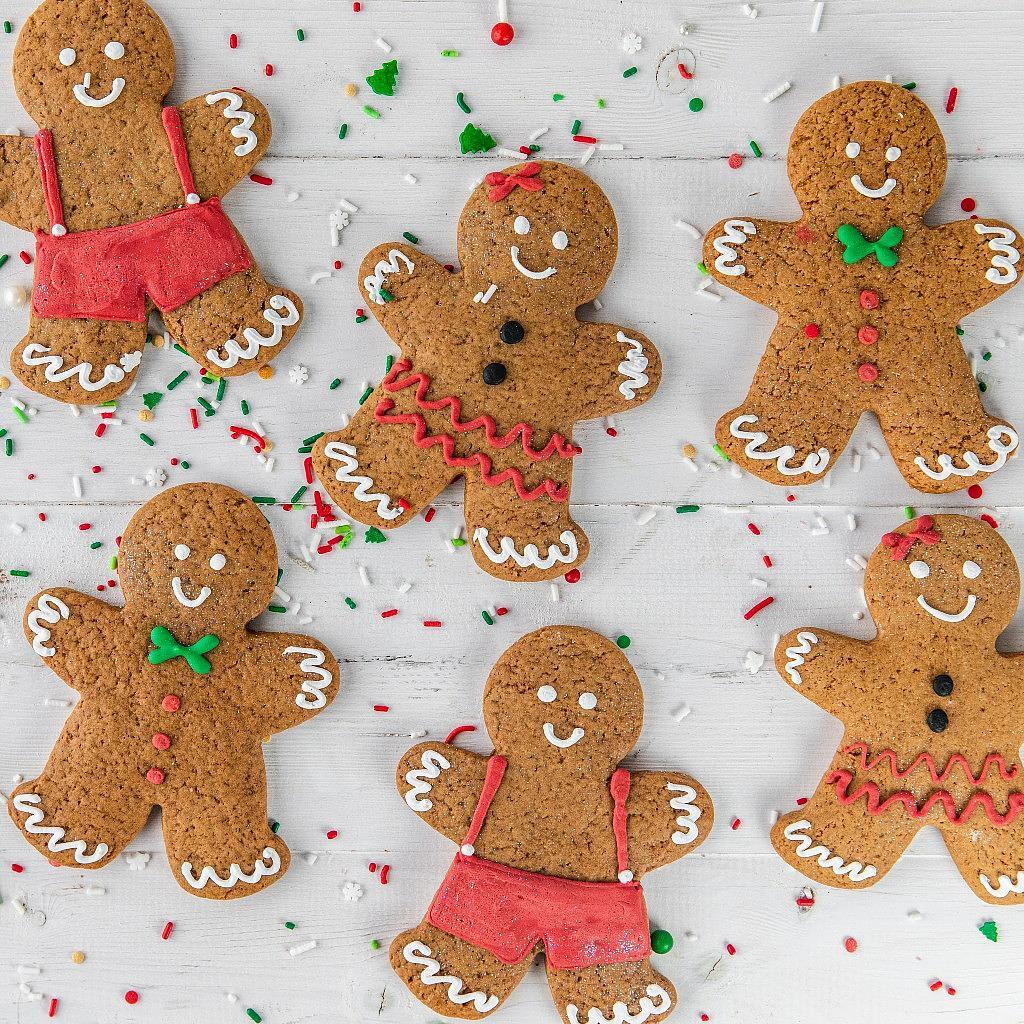 Christmas GingerPeople decorated with icing on white wood.